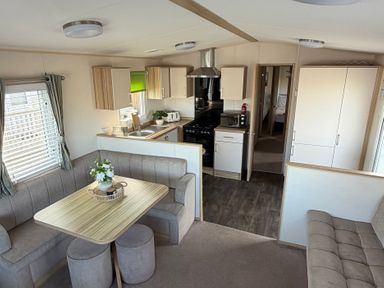 A kitchen area with a table and seating at The Beachside Hideout - St Michaels Caravan Park Towyn