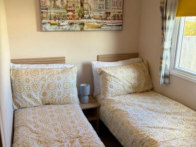 A bedroom with two beds and a painting at The Beachside Hideout - St Michaels Caravan Park Towyn