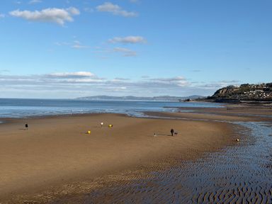 A beach with people walking near water at The Beachside Hideout - St Michaels Caravan Park Towyn