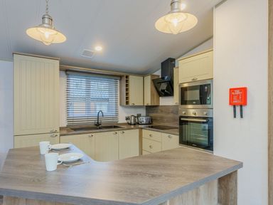 A kitchen with cabinets, sink, appliances, and dining items at Brayford Lodge (Pet) Louth