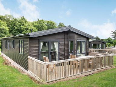 A lodge with a wooden deck and chairs at Brayford Lodge (Pet) in Louth