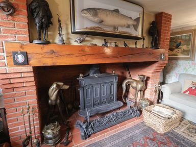 A living room with a brick fireplace and decorative features at Winston Lodge in Beccles
