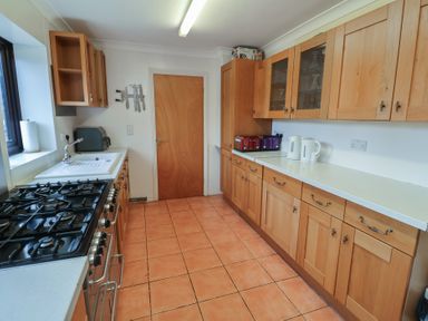 A kitchen with wooden cabinets and a gas stove at Winston Lodge in Beccles