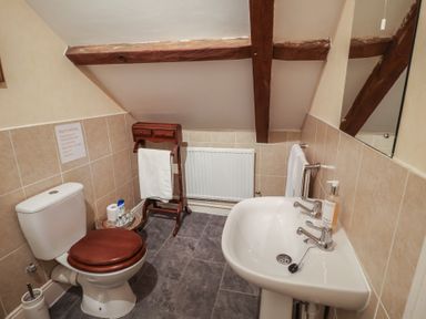 A bathroom with a toilet, sink, and towel rack at Winston Lodge in Beccles
