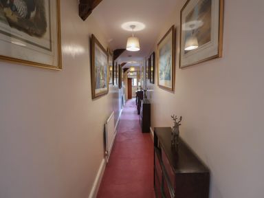 A hallway with framed pictures and a console table at Winston Lodge in Beccles