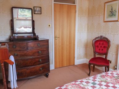 A bedroom with a dresser and a mirror at Winston Lodge in Beccles