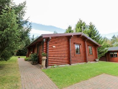 A log cabin with a pathway and garden area at Little Bears Hideaway @ 23 Lakeside Felmoor Park near Felton
