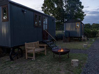 An outdoor area with shepherd's huts and a fire pit at No 1 The Orchard Upton Warren