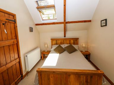 A bedroom with a double bed and wooden furniture at 1 Mill Farm Cottages in Narberth