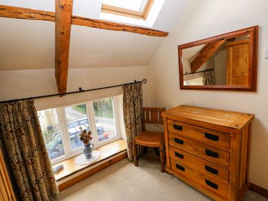 A bedroom with a dresser, chair, and window at 1 Mill Farm Cottages in Narberth