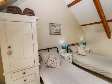 A bedroom with two beds and a wardrobe at 1 Mill Farm Cottages in Narberth