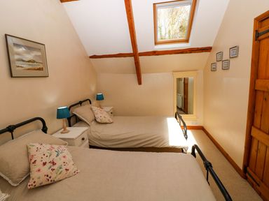A bedroom with two beds and a mirror at 1 Mill Farm Cottages in Narberth