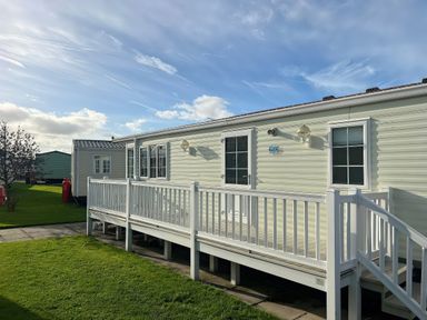 A mobile home with a deck and grassy area at Gainc Bach in Abergele