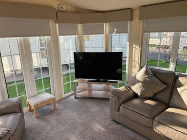 A snug with a sofa and television at Gainc Bach in Abergele