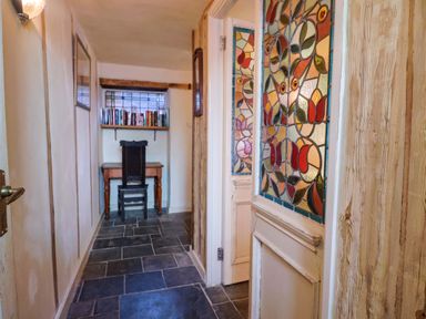 A hallway with stained glass windows and a desk at Rope Cottage in Bridport
