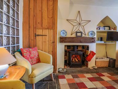 A living room with a fireplace and armchair at Rope Cottage in Bridport