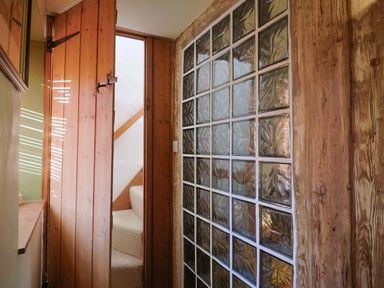 A hallway with a wooden door and glass block wall at Rope Cottage in Bridport