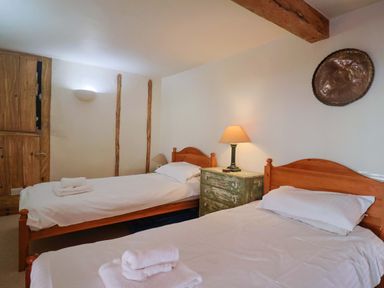 A bedroom with two beds and a nightstand at Rope Cottage in Bridport