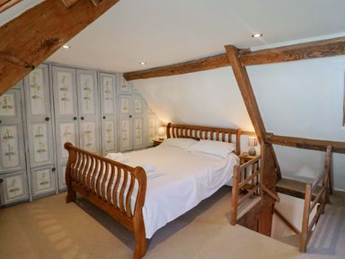 A bedroom with a bed and wardrobe at Rope Cottage in Bridport