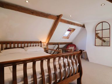 A bedroom with a bed and a chair at Rope Cottage in Bridport