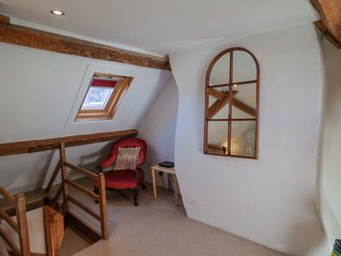 A landing area with a chair and window at Rope Cottage in Bridport