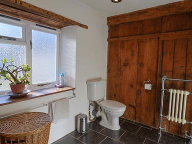 A bathroom with a toilet and a window at Rope Cottage in Bridport