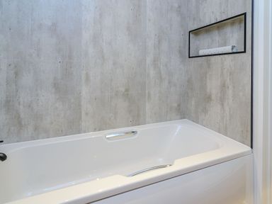 A bathtub with a shelf on the wall at The Castor in Kings Cliffe