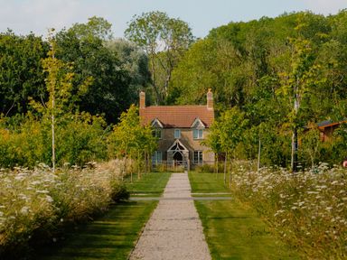 A house with a pathway surrounded by trees and garden at The Wansford in Kings Cliffe