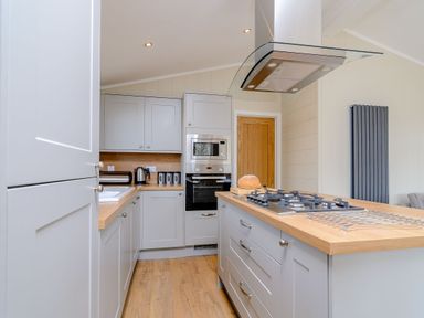 A kitchen with cabinets and an island showing an oven and stove at The Ailsworth (Pet) Kings Cliffe