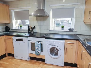 A kitchen with appliances including a dishwasher and washing machine at Beadlin cottage Beadnell