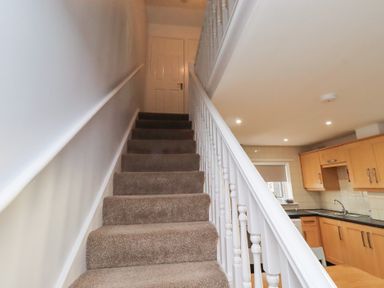 A staircase leading to a landing with a door at Beadlin cottage Beadnell