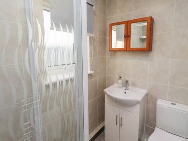 A bathroom with a shower, sink, and toilet at Beadlin cottage Beadnell
