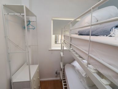 A bedroom with a bunk bed and storage unit at Beadlin cottage Beadnell