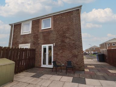 A house exterior with a patio and garden shed at Beadlin cottage Beadnell