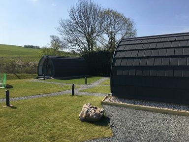 A garden with two camping pods and a pathway at Pod 1 (Pet Friendly) in Carnforth