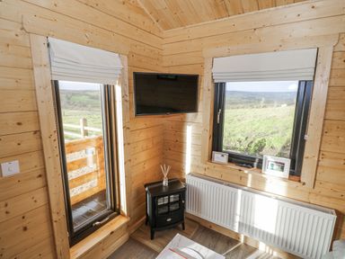 A snug with windows and a television at Glenview Log Cabin Ballycastle