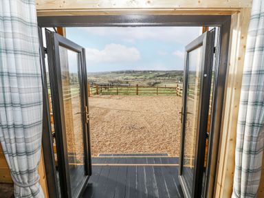 Double doors leading to a gravel area with a fenced landscape at Glenview Log Cabin in Ballycastle