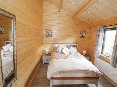 A bedroom with a bed and a mirror at Glenview Log Cabin in Ballycastle