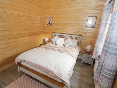 A bedroom with a bed and nightstand at Glenview Log Cabin in Ballycastle