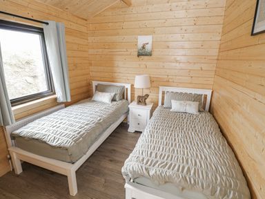 A bedroom with two beds and a bedside table at Glenview Log Cabin Ballycastle