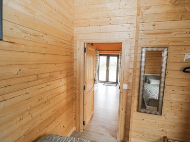 A bedroom entrance with wooden walls and a doorway at Glenview Log Cabin Ballycastle