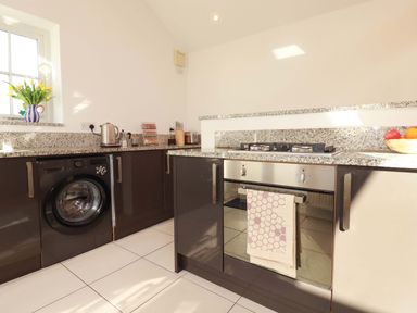 A kitchen with washing machine and gas stove at The Maisonette in Hayle