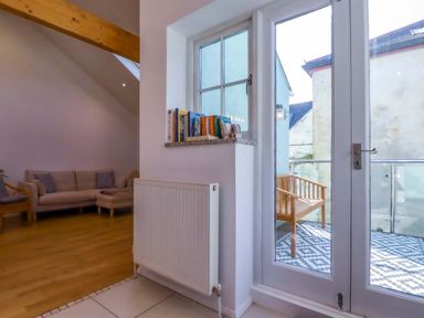 A living room with a sofa and books on a shelf at The Maisonette in Hayle