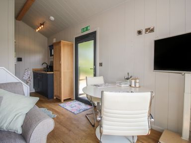 A living room with a sofa and dining area at Leafy Oaks Cabin in Munslow