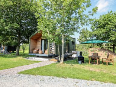 A cabin with chairs and a table in the garden at Leafy Oaks Cabin in Munslow