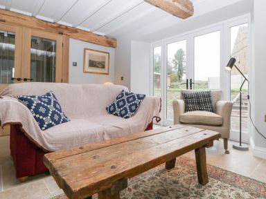 A snug with a sofa and armchair at Velindra Farm Cottage Hereford