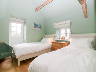 A bedroom with two beds and a chest of drawers at Velindra Farm Cottage Hereford