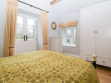 A bedroom with a bed and wardrobe at Velindra Farm Cottage Hereford