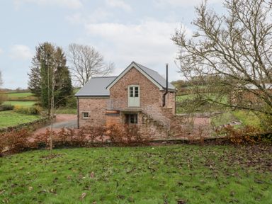 A house with a stone exterior and stairs leading to the door at Velindra Farm Cottage in Hereford