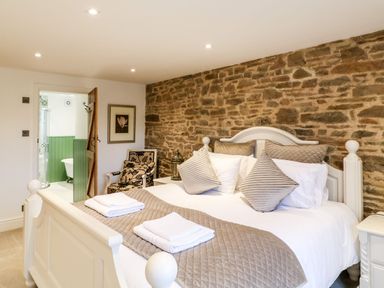 A bedroom with a double bed and stone wall at Lake View in Crediton